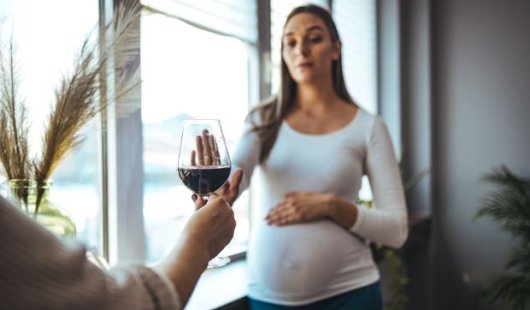 Pregnant woman declining glass of red wine. Adobe